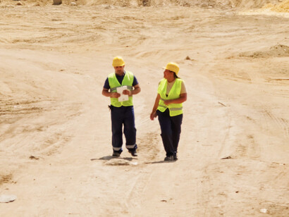 Two workers navigate a bustling construction site, embodying the industry's shift toward integrating sustainable practices and innovative design