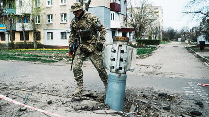 Soldado del Ejercito ucraniano caminando al lado de los restos de una bomba de guerra en Kiev, Ucrania