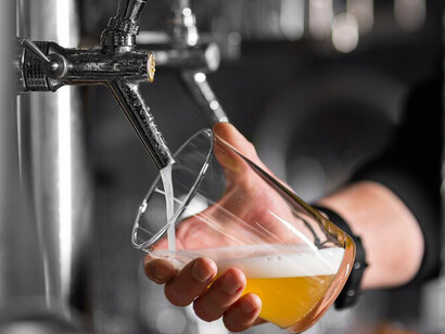 A bartender fills a glass with freshly poured beer from a keg, crafting the ideal pour with a rich, frothy head