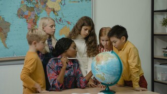 Professora demonstra a localização de país no globo terrestre. Os professores brasileiros se veem submetidos a jornadas extensas, que incluem a preparação de aulas, correção de atividades, planejamento burocrático e, muitas vezes, a condução de atividades adaptadas para alunos com necessidades especiais. Em escolas frequentemente superlotadas, a exigência de cumprir metas educacionais coloca a qualidade do ensino em segundo plano, agravando o estresse e contribuindo para a exaustão de muitos profissionais. Casos extremos, como de professoras que chegaram ao limite de sua resistência emocional e até faleceram em sala de aula, ilustram a gravidade dessa sobrecarga
