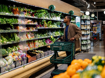 Man browsing fresh produce in a grocery store, illustrating consumer behavior and weekly shopping routines