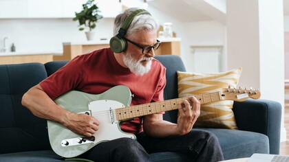 Senior man enjoying music while playing an electric guitar