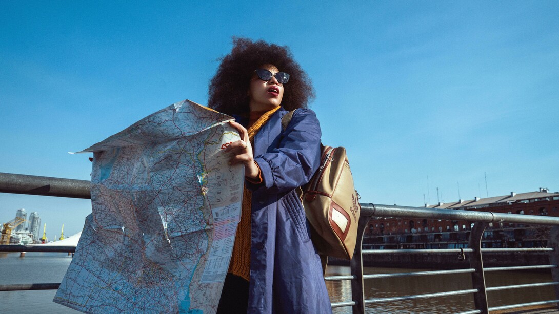 A woman stands on a bridge, studying a map as she plans her next destination