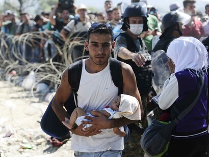 Un inmigrante sirio recién llegado con su hijo a las costas de Grecia