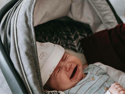 A baby in a stroller crying for lack of food and attention