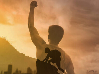 Strong young man climbs mountain in the city with fist in the sky