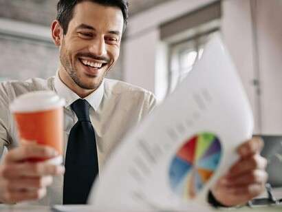 In the office, an entrepreneur reviews business reports and financial graphs, taking notes to assess stock market performance and craft informed options trading strategies