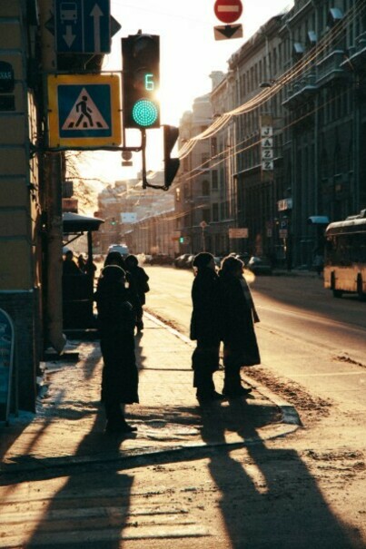 People standing at a crossroads on a sidewalk during sunset in Saint Petersburg, Russia