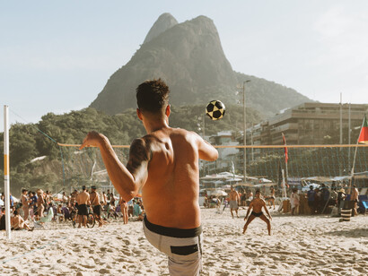 Cariocas jogam futvôlei na praia de Copabacana com vista para o morro do Pão de Açúcar no Rio de Janeiro, Brasil