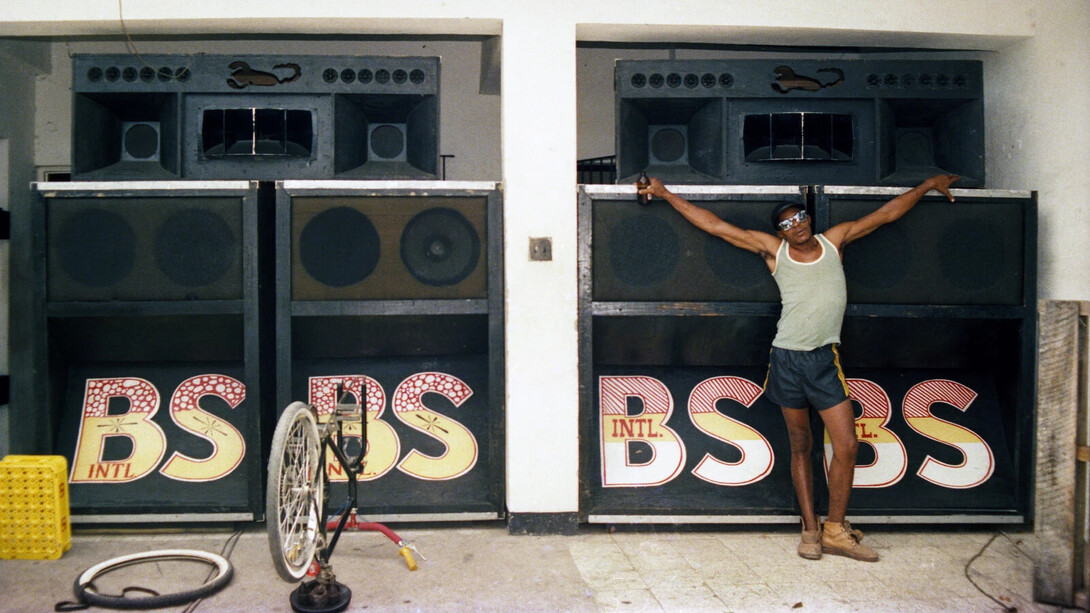 Beth Lesser, Papa Screw, selector for the Black scorpio sound system, in front of the speaker boxes in the Scorpio headquarters, Drewsland, Kingston, Jamaica (detail), 1985. Courtesy of MCA Chicago