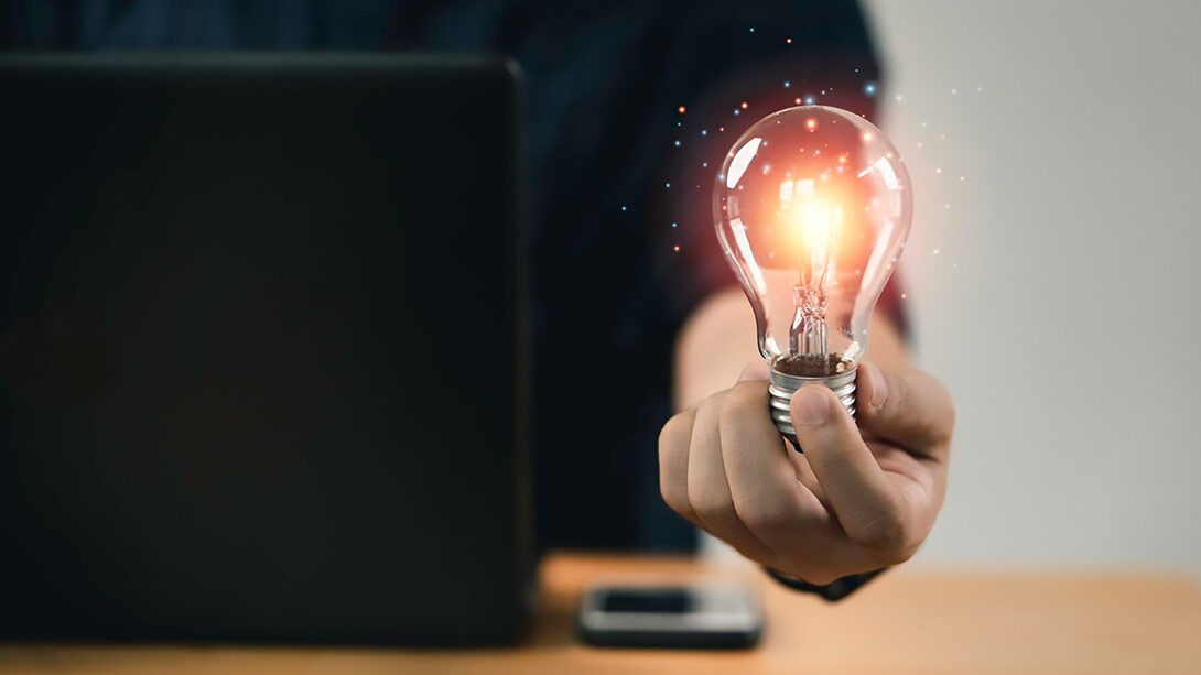 A businessman holding a glowing lightbulb, symbolizing creative thinking and the journey from failure to success, highlighting resilience, growth, and perseverance