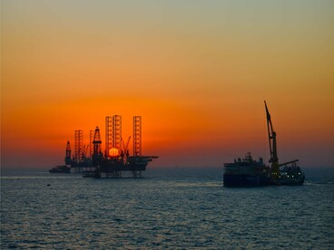 Oil rigs at the horizon at dusk, symbolizing the industries whose emissions have fueled the climate crisis