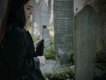A woman in a cemetery staring at the buried