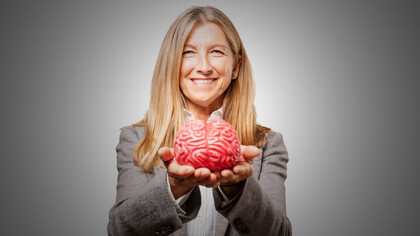 A woman holding a brain in her hands, symbolizing the complex decision-making processes discussed in the article