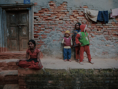 Children playing outside a weathered brick building in a residential area
