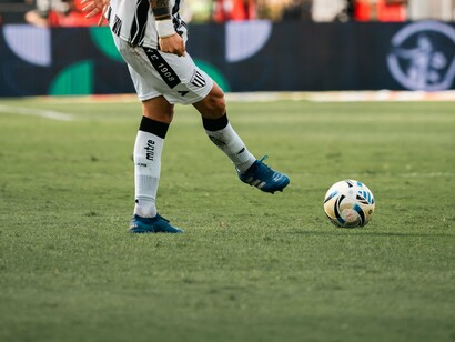 Um jogador com uniforme alvinegro se movimenta em direção à bola, preparando-se para executar uma jogada durante a partida. A cena destaca a importância do domínio técnico e da movimentação para superar os adversários. Na nova etapa de sua carreira, Gabigol precisará transformar sua capacidade ofensiva em atuações consistentes para conquistar espaço no Santos