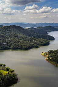 Vista aérea do reservatório Atibainha, um dos cinco lagos que compõem o sistema Cantareira, principal fonte de água potável para a cidade de São Paulo. A Mata Atlântica influencia diretamente a vida das pessoas ao fornecer água, regular o clima e proteger encostas contra deslizamentos. No entanto, a urbanização desordenada e o desmatamento continuam a ameaçar esse bioma tão importante