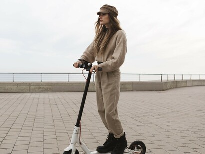 A young woman riding an electric scooter along a peaceful, walkable city street