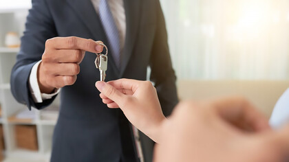 A beaming couple receiving the keys to their new house from a real estate professional, capturing the joy of homeownership