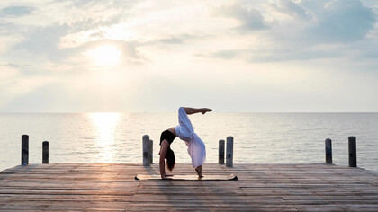 Mujer practicando yoga cerca del mar