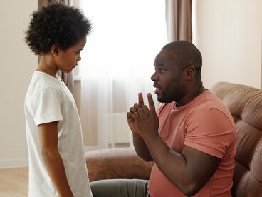 A child listening intently to a parent's words, symbolising the lessons and beliefs quietly absorbed during the early years