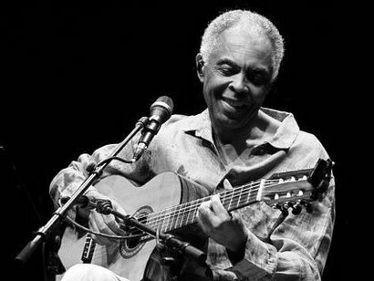 Sentado ao violão, Gilberto Gil se concentra durante apresentação no Auditório Ibirapuera. O instrumento, tão presente em sua trajetória, atravessa também as lembranças do autor, desde as primeiras descobertas das canções de Gil até os shows compartilhados com a família
