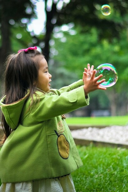 Young girl trying to catch a bubble