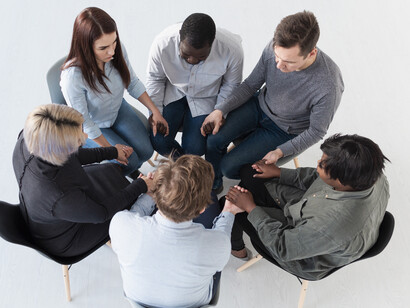 An overhead view of people forming a circle with raised hands, representing cooperation, interconnectedness, and collective action