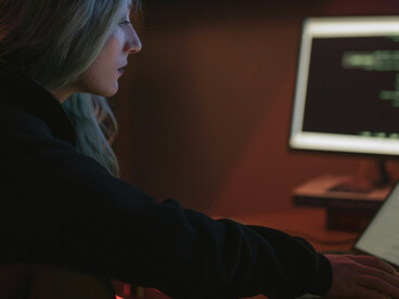 A woman typing on a keyboard, working as a programmer