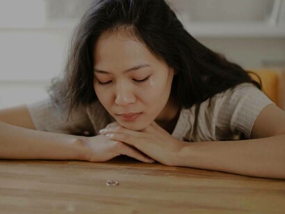 A woman staring at the ring she removed after she uncovered that her partner cheated on her