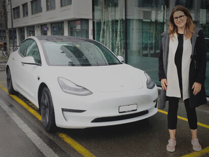 A woman stands proud in front of her white EV