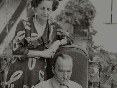 Nikos Kazantzakis is sitting and reading while being observed by his wife Eleni Samiou
