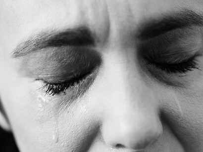 Tears streak down tightly shut eyes, capturing the quiet collapse of a soul who has seen too much