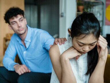 A couple having a quiet argument on the sofa, each feeling unheard and misunderstood
