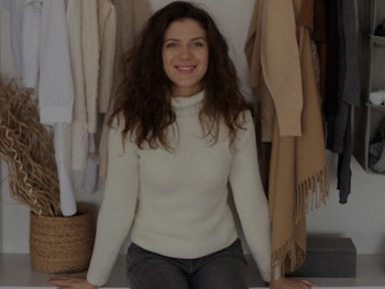 A woman standing in front of a wardrobe, modeling a cozy white sweater