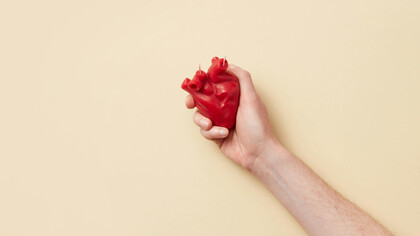 A red heart held tightly on one hand