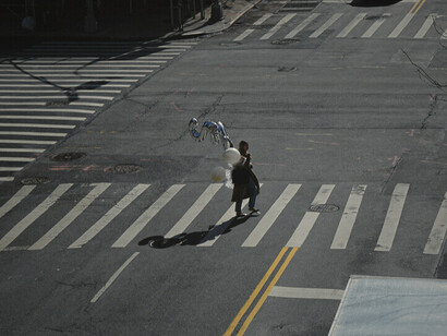 Une femme marchant avec des ballons sous un soleil éclatant, soulignant les contrastes dans la vie quotidienne des habitants de Bamako, où la pénurie de carburant affecte la vie de tous, même dans les moments de légèreté