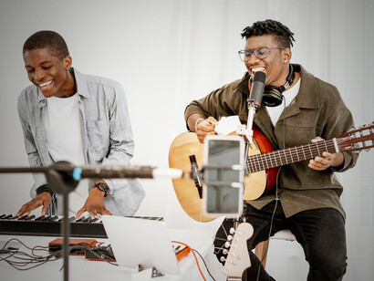 Amapiano music with a striking image of male musicians at home, playing guitar and piano from a front view, capturing the essence of the vibrant amapiano music scene
