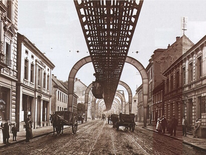 Die Schwebebahn fährt entlang der Hauptstraße in Sonnborn (heute Sonnborner Straße) und zwischen den Bogenträger Nr. 90 und Nr.89, ca. 1903