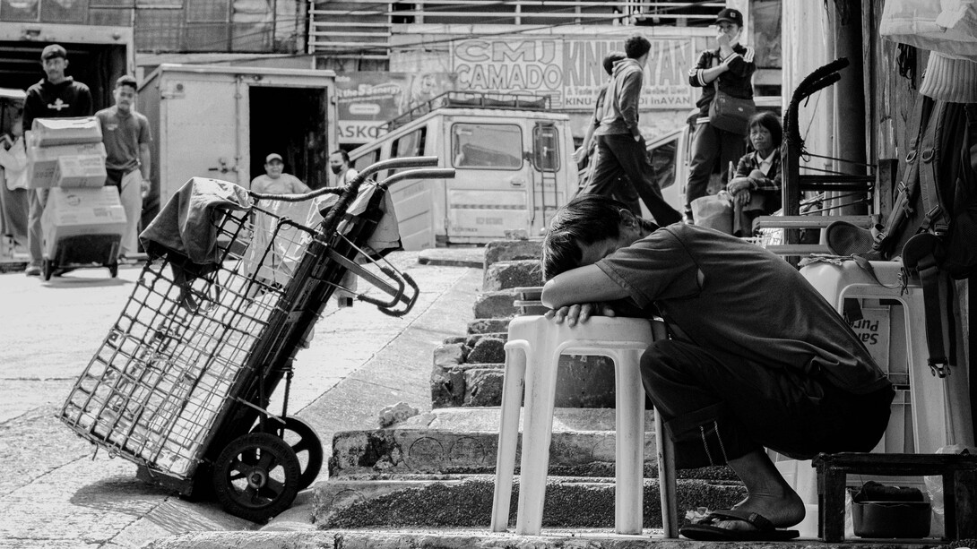 An exhausted worker resting beside a handcart, representing the daily burden ordinary Filipinos carry while institutions struggle to ease their hardships