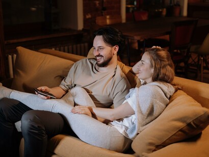 Couple chilling on the couch watching tv, cuddling together in the evening at home
