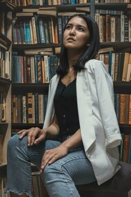 A woman sits in an academic library in Asia, surrounded by shelves filled with books