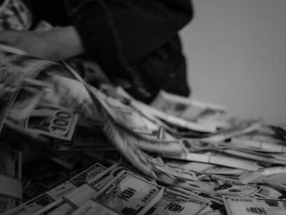 Hands holding US dollar bills — a metaphor for corruption and systemic failure