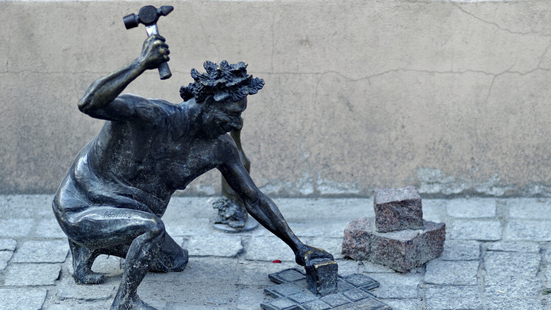 Statue of a mason, using his hammer on the walkway