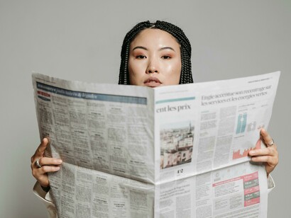 A woman with braided hair reading a newspaper