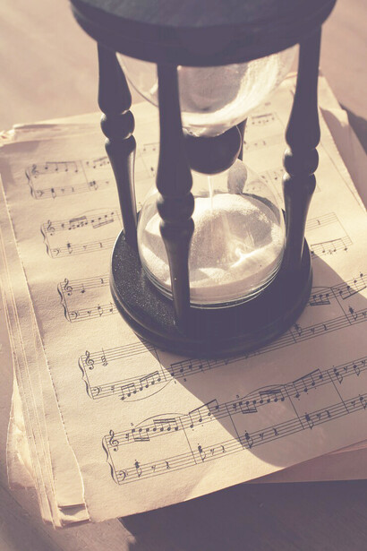 Music notes are scattered across papers next to an hourglass, capturing the essence of time and music intertwined