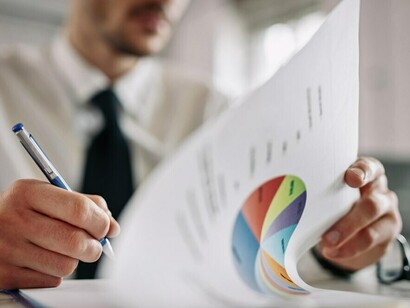 An entrepreneur reviewing business reports and taking notes in the office, analyzing stock market trends, options trading, and financial graphs to develop effective trading strategies