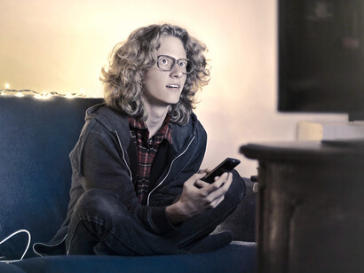 Jovem distraído usando smartphone e assistindo TV na sala de estar