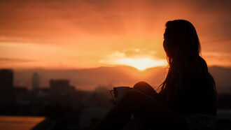 Silueta de una mujer mirando hacia el atardecer