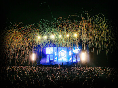 Concertgoers experience a light show as the concert begins and the lights begin to shower down